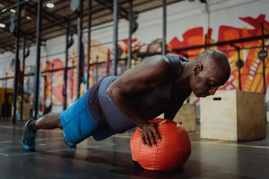 Un homme faisant des pompes sur un ballon d'exercice dans une salle de sport.