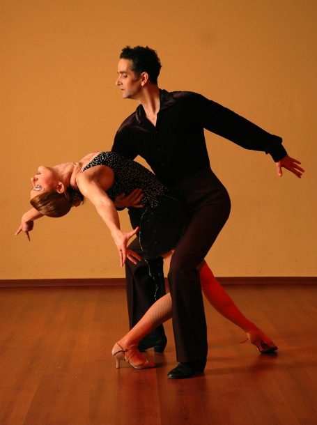 Danseurs en couple exécutant une pose expressive dans un studio avec un sol en bois.
